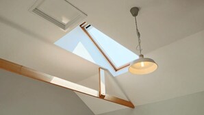 A skylight, a ceiling fan, and a pendant light fixture in a room with white walls. - Coach House in Clifton village (Bristol City)