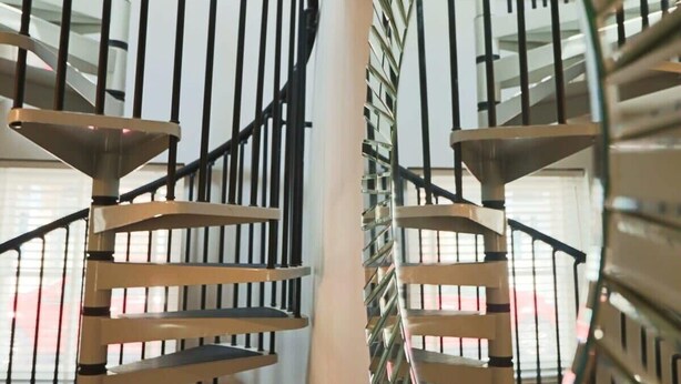 A spiral staircase with black railings and beige steps, leading to an upper floor. - Coach House in Clifton village (Bristol City)