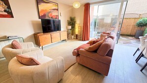 A living room with a sofa set, a TV, a cabinet, and a sliding glass door leading to an outdoor area. - Three bedroom House Next to Cabot Circus - Hopewell (Bristol)