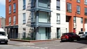 A modern multi-story building with a mix of brick and white facade, large windows, and a flat roof. - Three bedroom House Next to Cabot Circus - Hopewell (Bristol)
