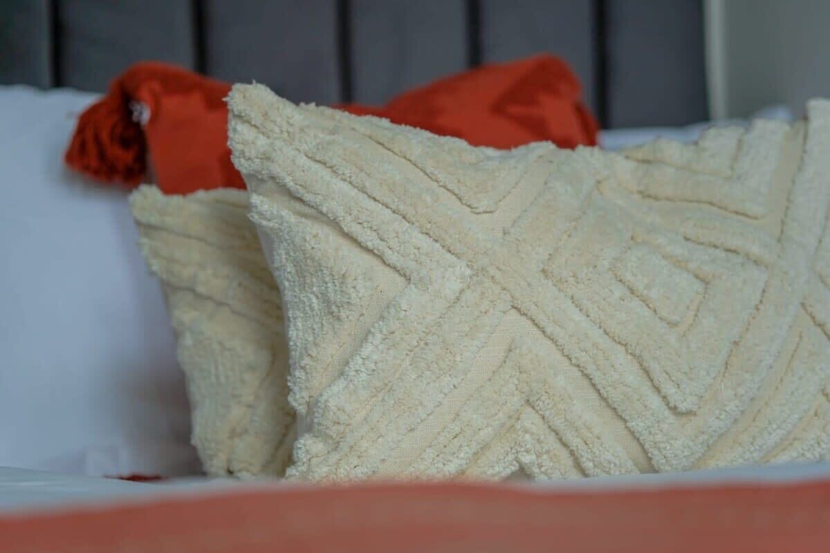Een bed met witte kussens en een rood kussen.