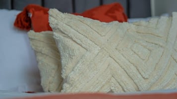 Een bed met witte kussens en een rood kussen.