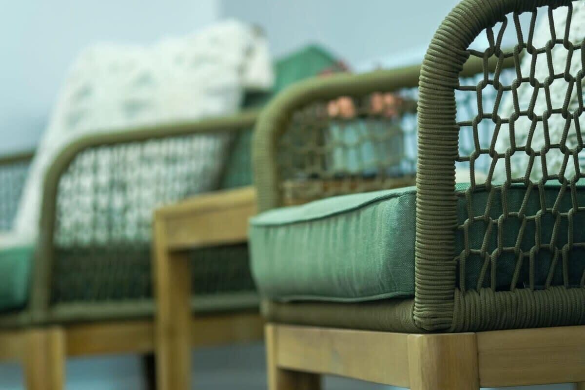 Wicker chairs with cushions and a netted backrest.
