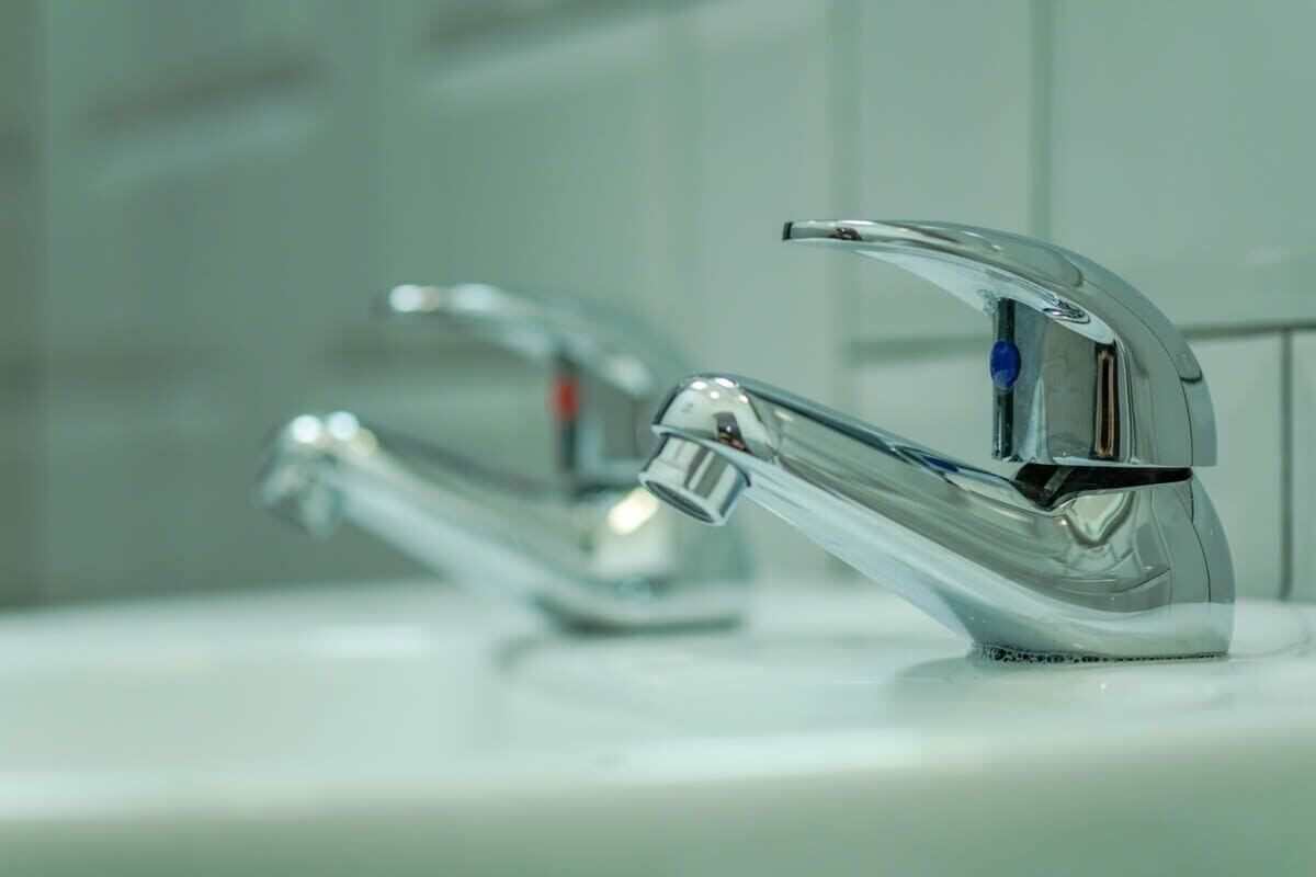 Un baño moderno con grifería cromada y encimera blanca.