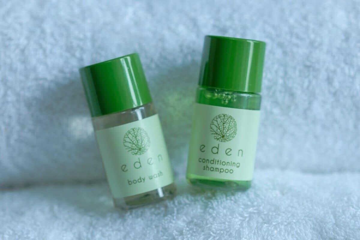 Two bottles of Eden body wash and conditioning shampoo on a white textured surface.