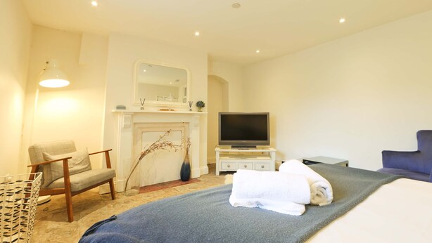 Une chambre d’hôtel équipée d’un lit, d’une télévision, d’une chaise, d’une petite table et d’une cheminée.