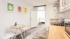 Une cuisine moderne avec des meubles blancs, un plan de travail en bois et un petit coin repas comprenant une table ronde et des chaises.