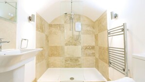 Une salle de bain avec une douche, un lavabo et un porte-serviettes.