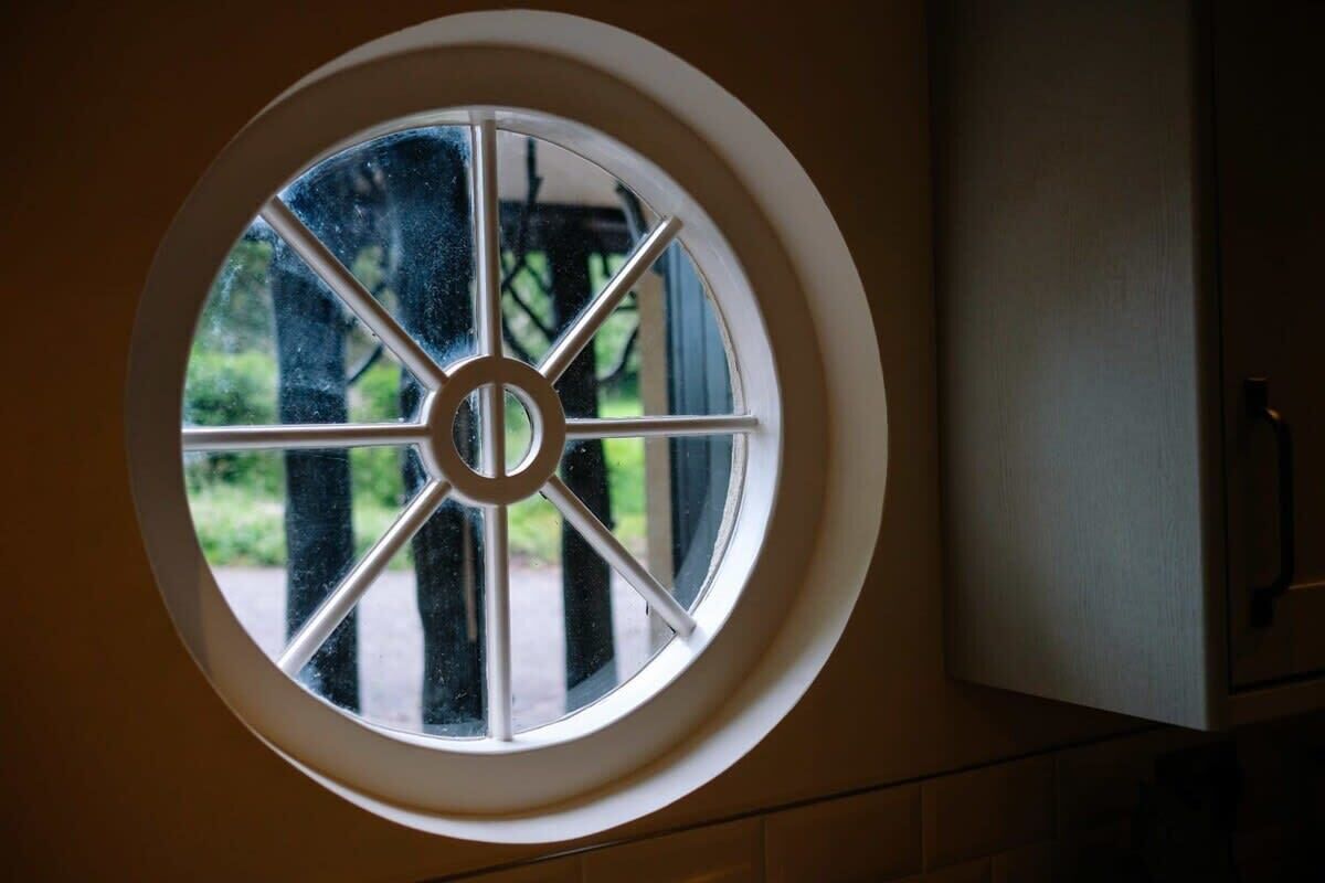 A round window with a central circular design and six panes, part of a building's exterior.