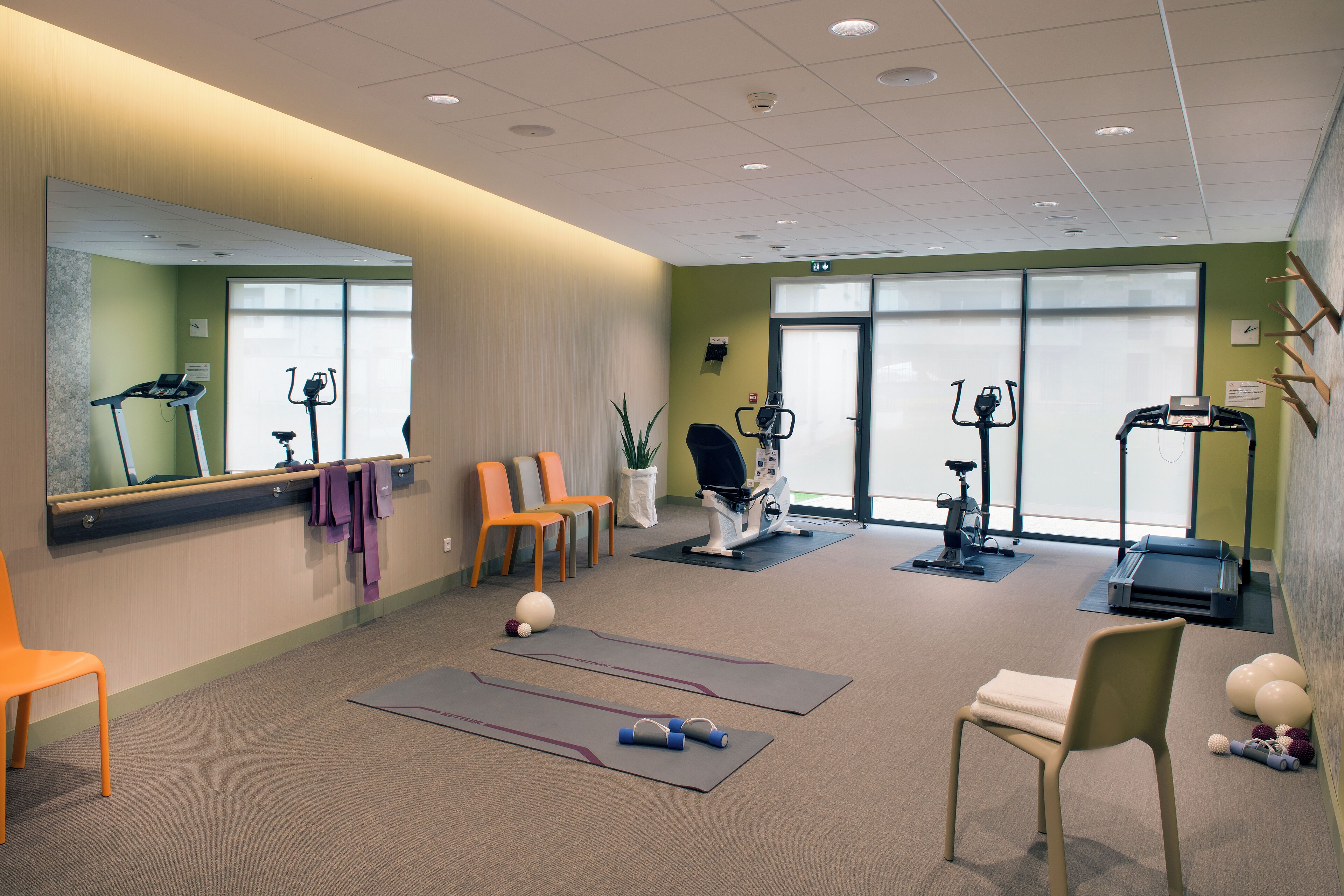 A fitness room with exercise equipment, mats, and chairs.