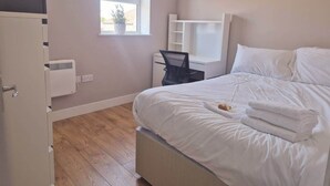 Una habitación de hotel con cama, escritorio, silla, ventana y armario.