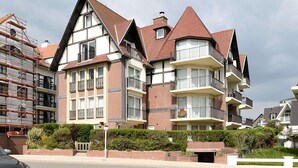 A multi-story residential building with a symmetrical facade, multiple balconies, and a brick exterior. - Clipper 0202 Tasteful Apartment (De Haan)