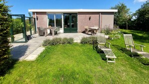 A modern house with a patio, outdoor seating, and a garden. - Modern Bungalow Close to Beach With Views (Sint Maartensvlotbrug)