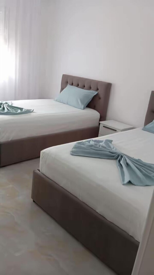 A hotel room with two beds, each with a headboard and a pillow.