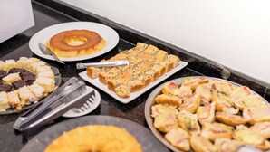 Una mesa de buffet con diversos platos, incluyendo un donut, un pastel y varios tipos de aperitivos.