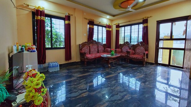 A spacious room with a marble floor, a sofa set, a small table, and a decorative vase. - Tathagata Homestay (Lumbini)
