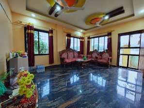 A spacious room with a marble floor, a sofa set, a small table, and a decorative vase. - Tathagata Homestay (Lumbini)