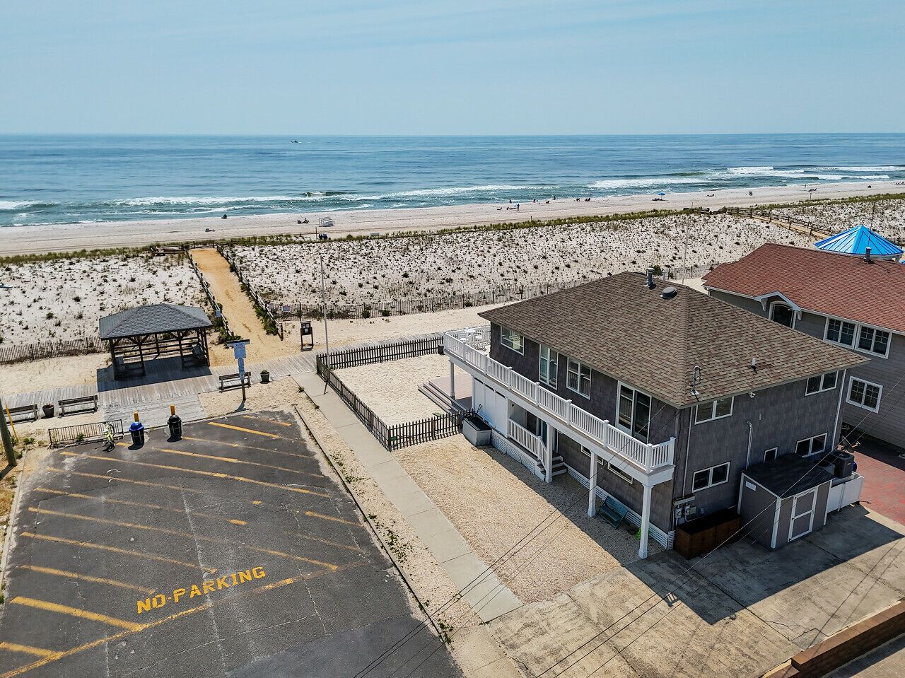 Un edificio frente a la playa con estacionamiento, una playa al fondo y cielo despejado.