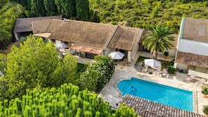 A villa with a swimming pool, multiple rooms with tiled roofs, and lush greenery surrounding the property.