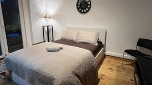 A bedroom with a bed, a clock on the wall, a lamp, and a chair. - Room-charming Guest Room in Historic Bru (Brussels)