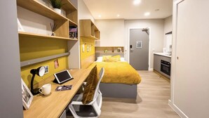 Un dormitorio moderno con cama, escritorio y kitchenette.