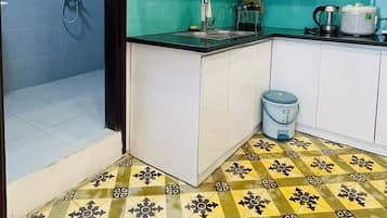 A kitchen with white cabinets, a green backsplash, a patterned floor, and a coffee maker.