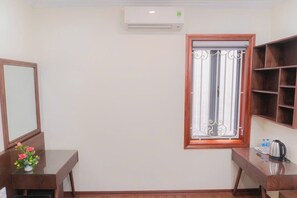 A room with a wooden desk, a mirror, a window with decorative bars, and a built-in shelf.