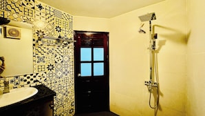 Une salle de bain avec un mur carrelé, un lavabo, un miroir et une douche.
