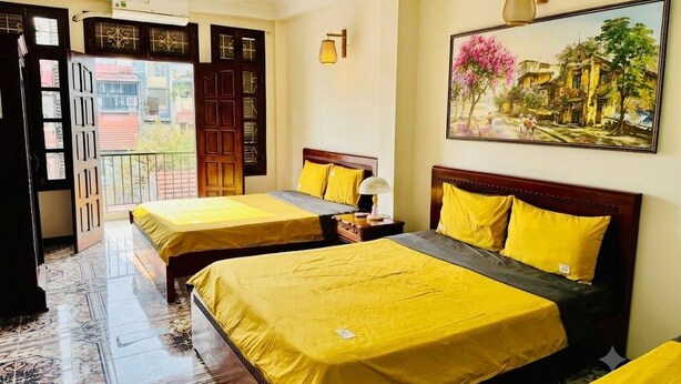 Een hotelkamer met twee bedden, een balkon en een schilderij aan de muur.