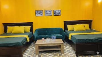 A room with two beds, a sofa, and a coffee table.