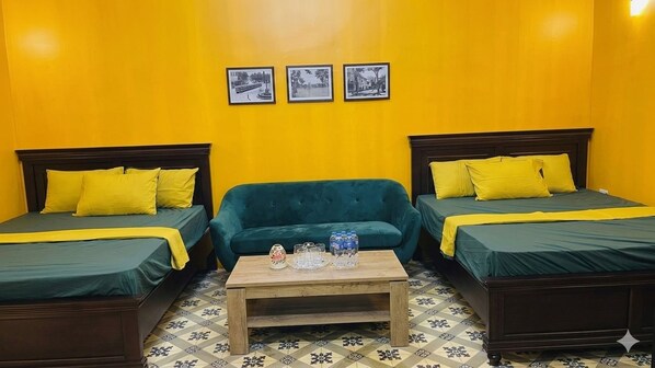 A room with two beds, a sofa, and a coffee table.