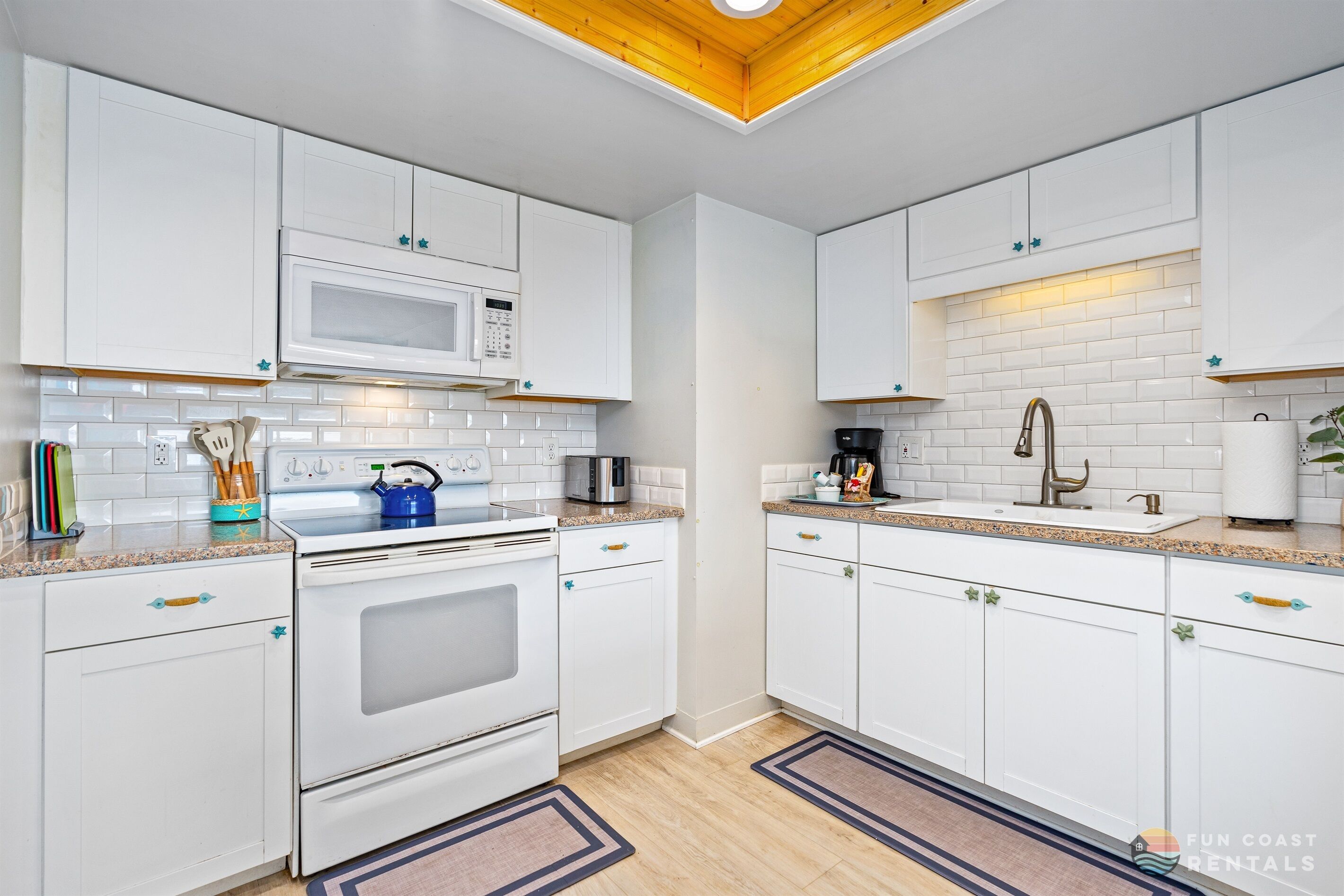 A modern kitchen with white cabinets, a microwave, stove, and a sink.