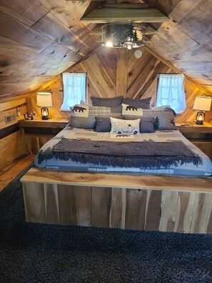A cozy, wooden-themed bedroom with a large bed, two bedside tables with lamps, and a ceiling light fixture. - Mountian “Silo-tude” (Sevierville)