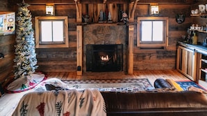 A cozy log cabin interior with a fireplace, wooden walls, and a Christmas tree. - Mountian “Silo-tude” (Sevierville)