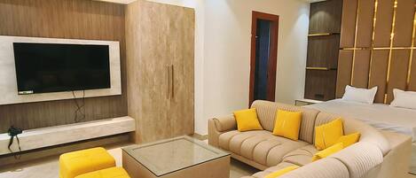 A modern living room with a sectional sofa, a glass coffee table, and a flat-screen TV mounted on the wall.