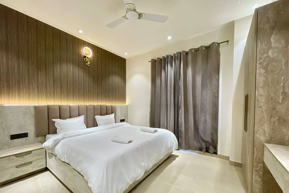 Un dormitorio moderno con una cama grande, un ventilador de techo y un aplique de pared.