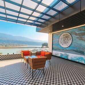 Una terraza con suelo a cuadros, muebles de mimbre y una gran obra de arte circular en la pared.