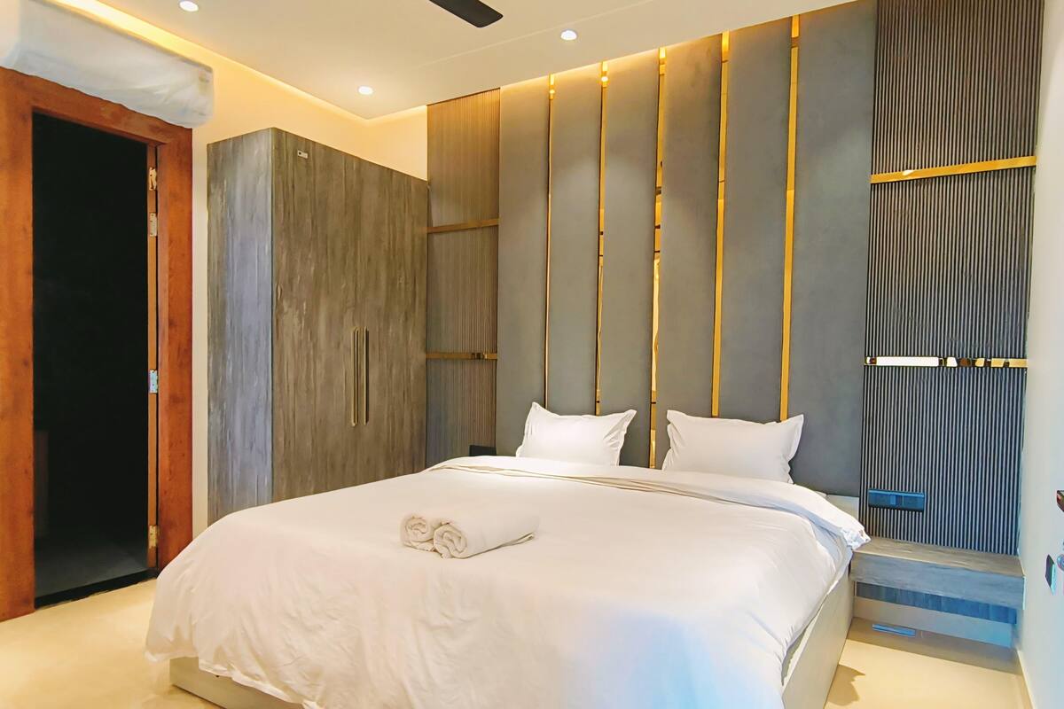 Un dormitorio moderno con una cama grande, un ventilador de techo y un armario de madera.