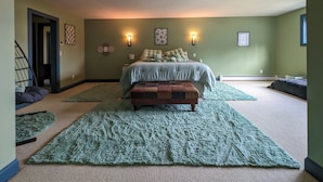 Un dormitorio con una cama, dos apliques, una alfombra y un banco.