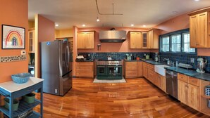 Una cocina con armarios de madera, un refrigerador de acero inoxidable, una estufa y un lavamanos.