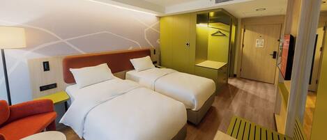 A hotel room with two beds, a sofa, a desk, and a bathroom.