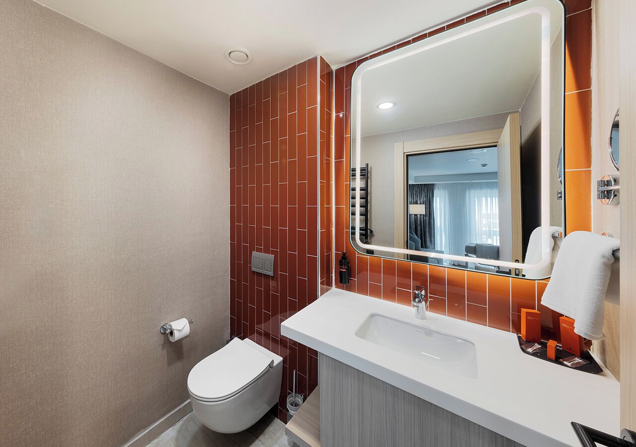 A modern bathroom with a white toilet, a white sink, and a mirror with a rectangular frame.