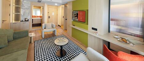 A modern living room with a sofa, chairs, a coffee table, and a kitchen area with a sink and cabinets.