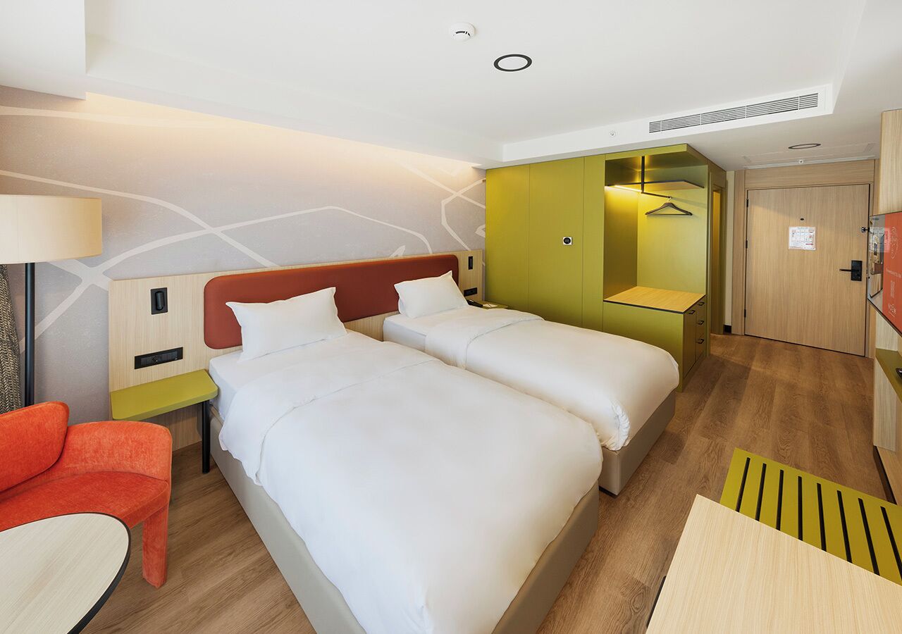 Une chambre d’hôtel avec deux lits, un canapé, un bureau et une armoire.