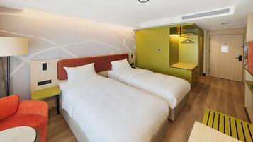 Une chambre d’hôtel avec deux lits, un canapé, un bureau et une armoire.