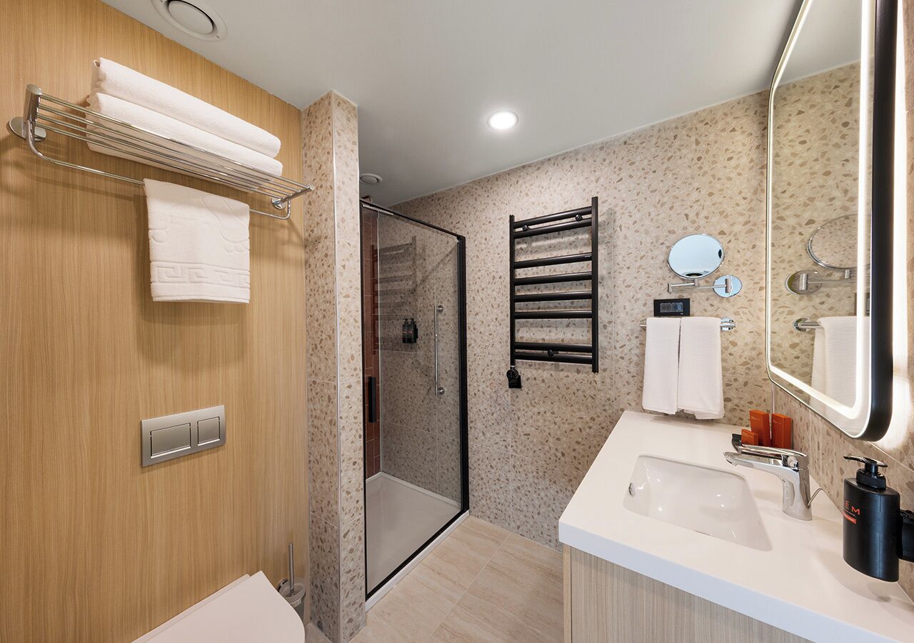 Un baño moderno con ducha, lavamanos y espejo.