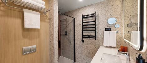 Un baño moderno con ducha, lavamanos y espejo.