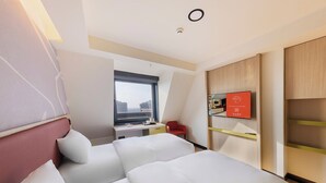 Habitación de hotel con cama, escritorio, silla, televisor y ventana con vistas.