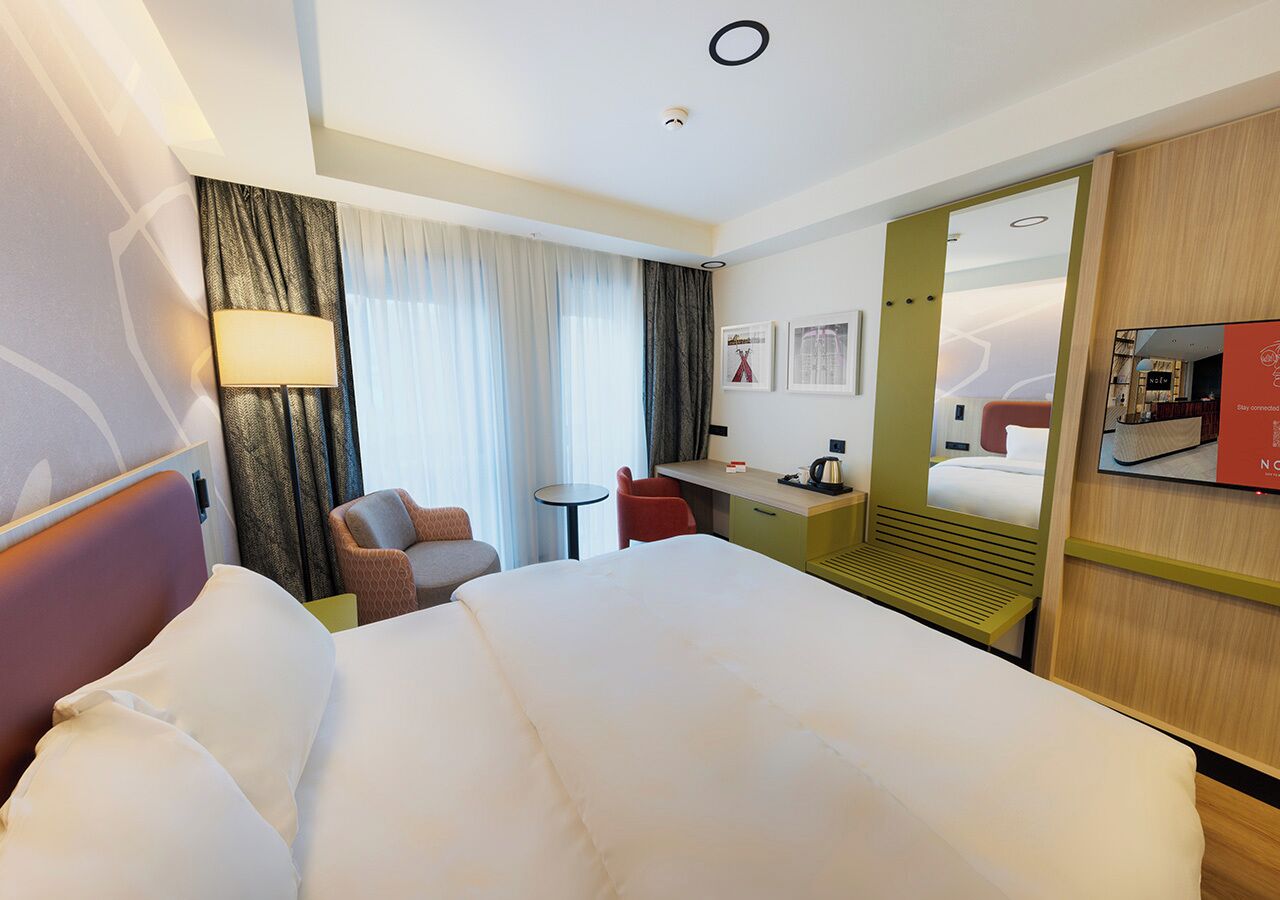 Une chambre d’hôtel avec un grand lit, un bureau, une chaise et une petite table.