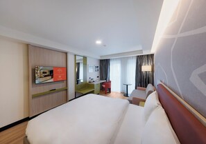 Una habitación de hotel con una cama grande, un escritorio, una silla y una mesita.